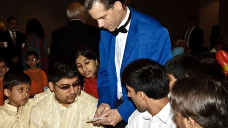 Magician performing a card trick during a close-up magic performance for children and families.