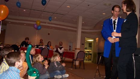 The magician and a volunteer entertain a family audience of both children and adults!