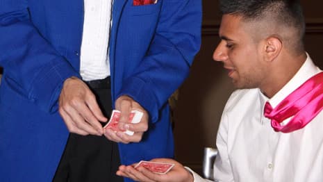 An adult volunteer helps a magician perform a funny-looking mini illusion!