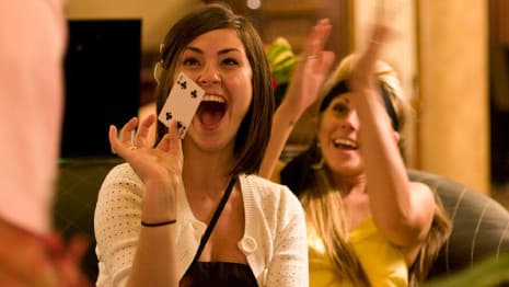 Magician performs a Close-up card trick for excited ladies.